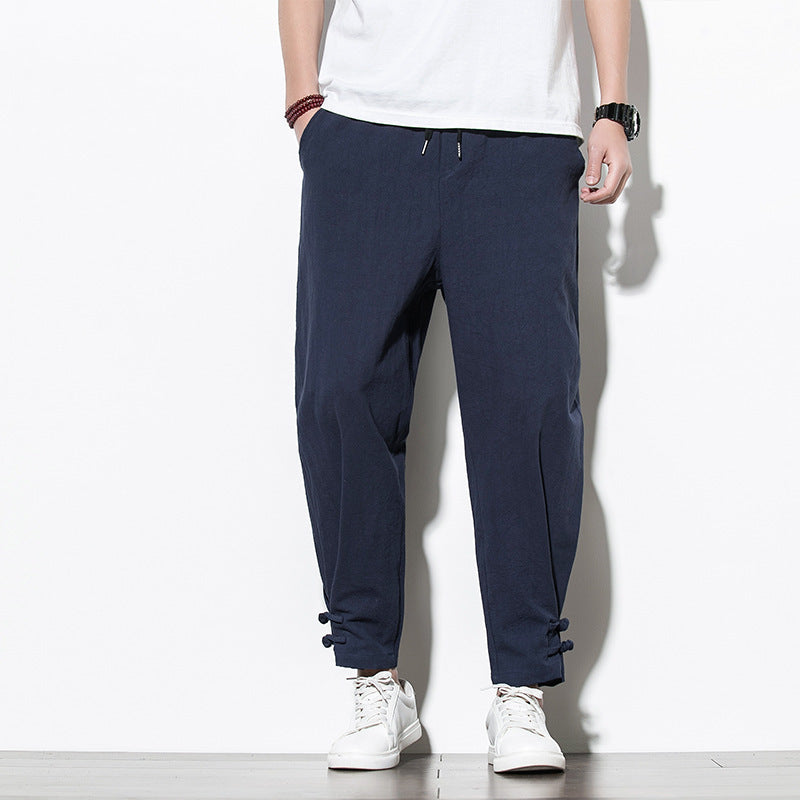 Person wearing navy blue jogger pants with a white background