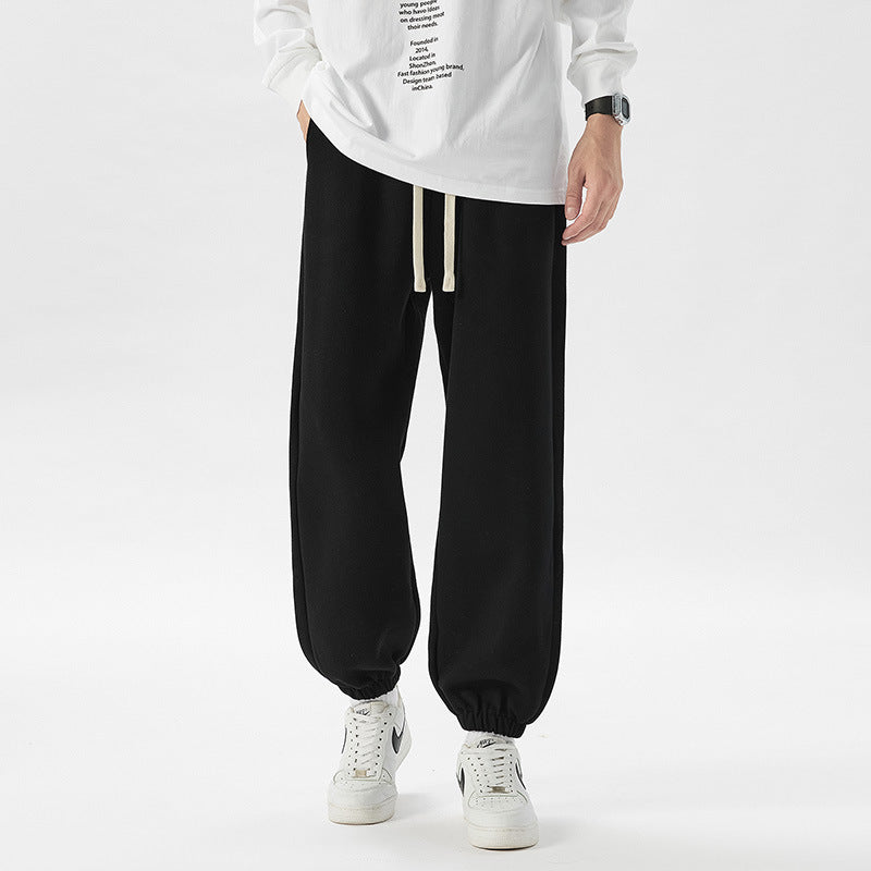 Person wearing black jogger pants and a white sweatshirt on a white background