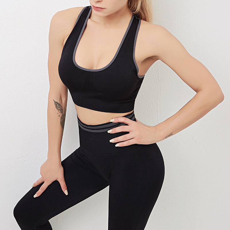 Woman wearing a black sports bra and leggings on a light gray background